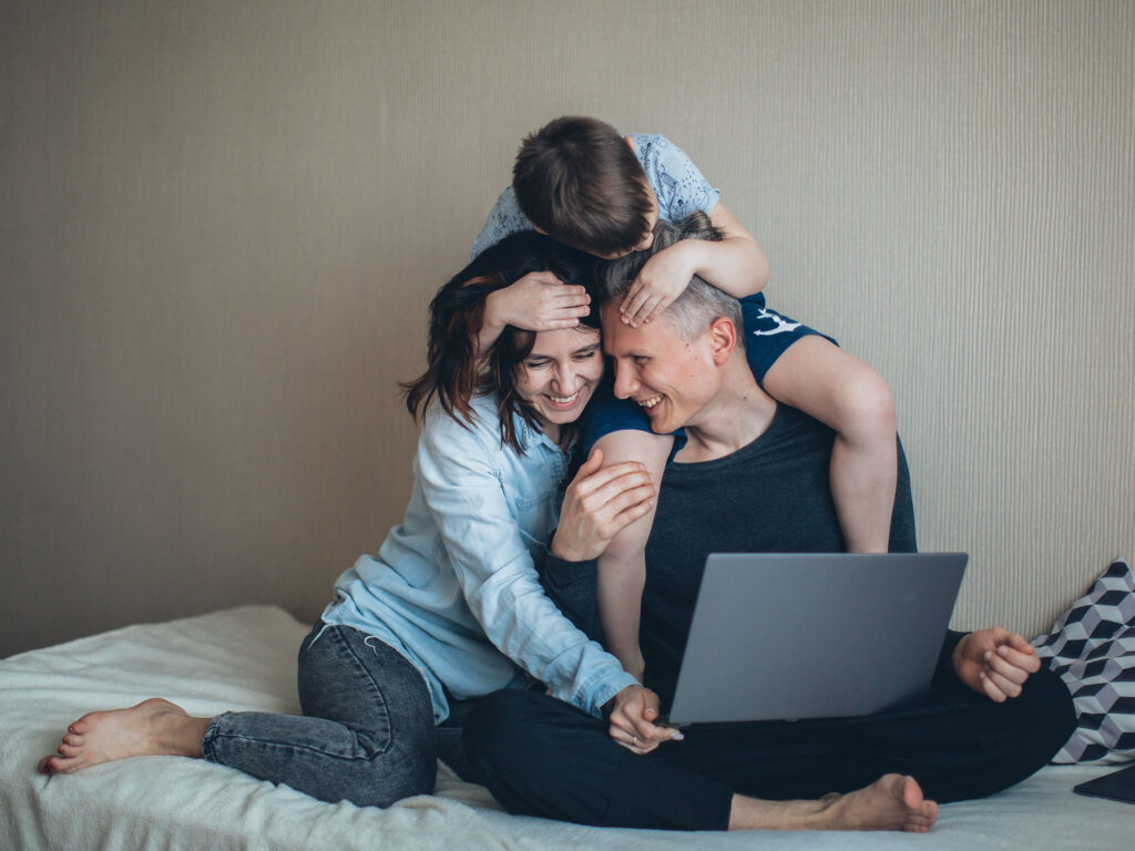 Family in front of laptop cuddling after having read The Ultimate Resource for Kids Online Safety