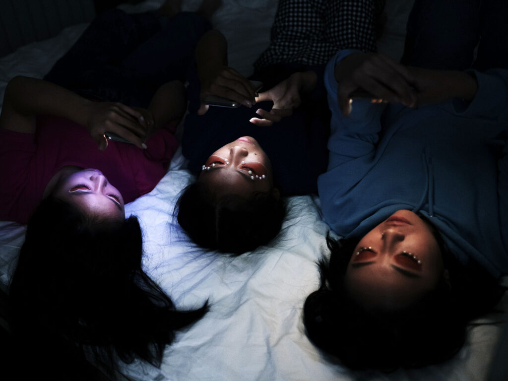 Three children staring at their phones engrossed in screen time